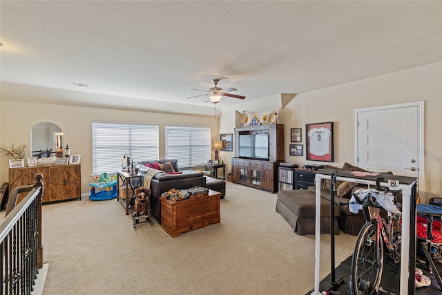 living room featuring ceiling fan, light colored carpet, and a textured ceiling