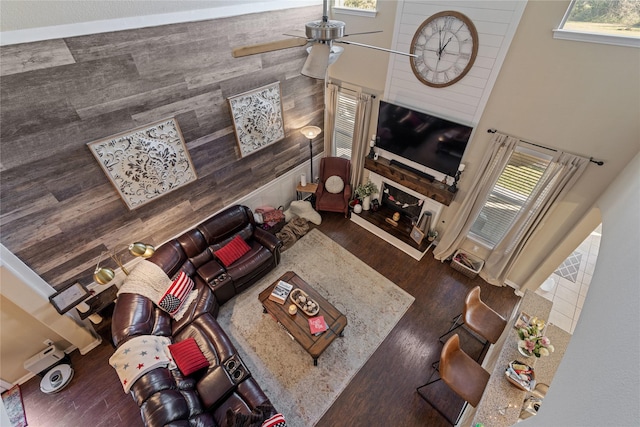 living room featuring dark wood-type flooring, a wealth of natural light, wooden walls, and ceiling fan