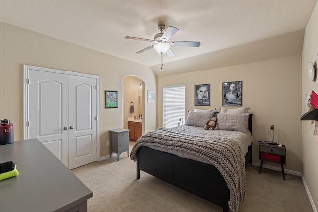 carpeted bedroom with ceiling fan, vaulted ceiling, connected bathroom, and a closet