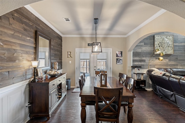 dining room with crown molding, french doors, dark wood-type flooring, and wooden walls