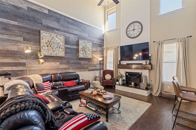 living room with dark hardwood / wood-style floors, wood walls, plenty of natural light, and a fireplace