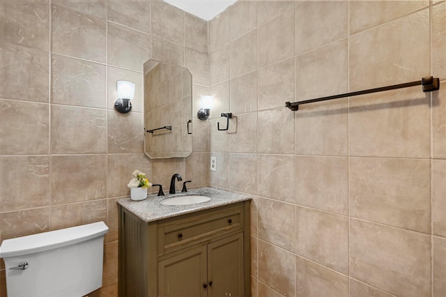 bathroom featuring vanity, toilet, and tile walls