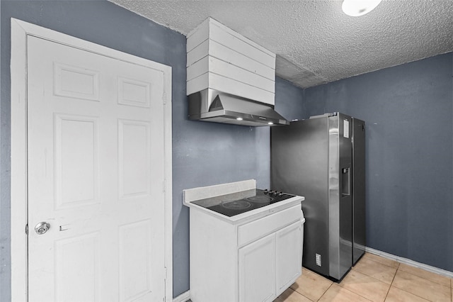 kitchen with wall chimney exhaust hood, white cabinets, stainless steel refrigerator with ice dispenser, a textured ceiling, and light tile patterned floors