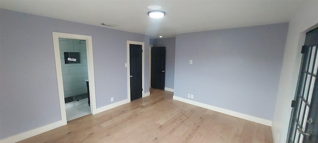 unfurnished bedroom featuring connected bathroom and light wood-type flooring