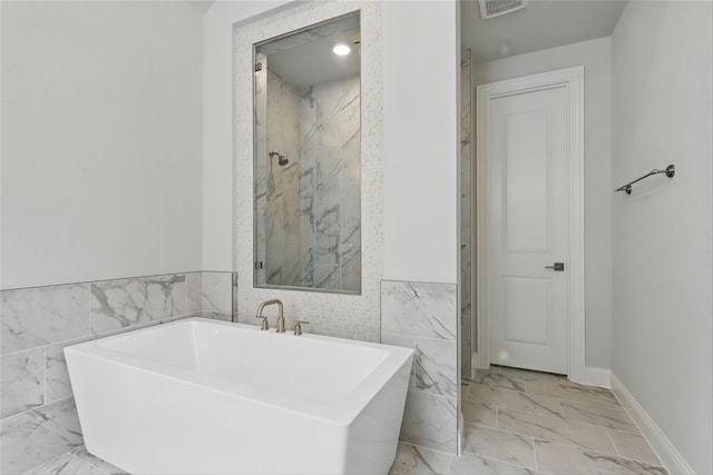 6300 Whitebrush Pl, Fort Worth, TX 76123 - full bath with marble finish flooring, a freestanding tub, tile walls, and wainscoting