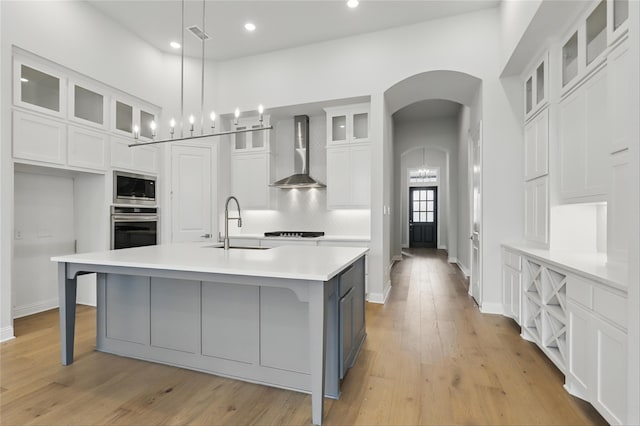 6300 Whitebrush Pl, Fort Worth, TX 76123 - kitchen with wall chimney range hood, appliances with stainless steel finishes, light countertops, white cabinetry, and arched walkways