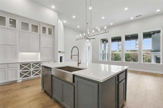 6300 Whitebrush Pl, Fort Worth, TX 76123 - kitchen with a sink, stainless steel dishwasher, gray cabinetry, light countertops, and an island with sink