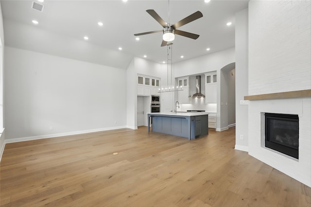 6300 Whitebrush Pl, Fort Worth, TX 76123 - kitchen with wall chimney range hood, white cabinets, ceiling fan, open floor plan, and a towering ceiling