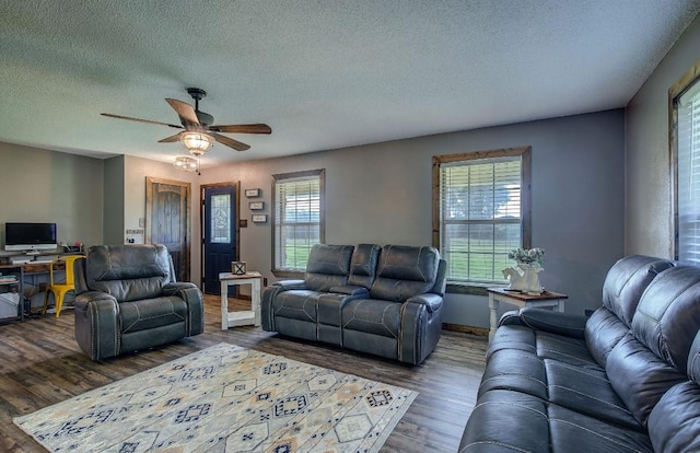 living room featuring ceiling fan, plenty of natural light, dark hardwood / wood-style floors, and a textured ceiling