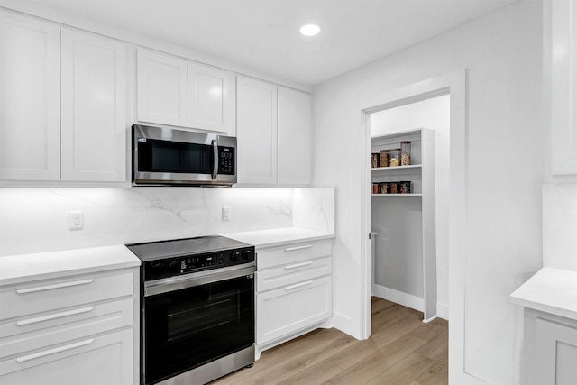 kitchen featuring light wood-type flooring, stainless steel appliances, and white cabinetry