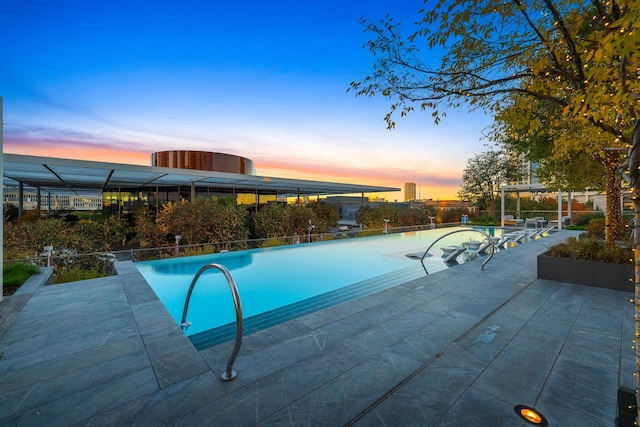 pool at dusk with a patio area