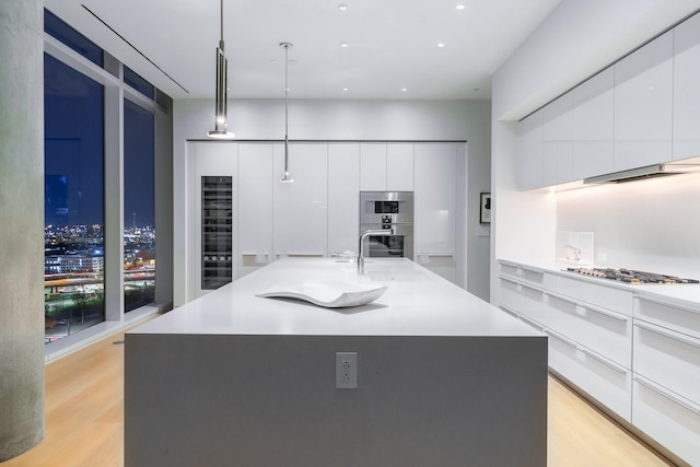 kitchen with a spacious island, white cabinetry, pendant lighting, and light hardwood / wood-style floors