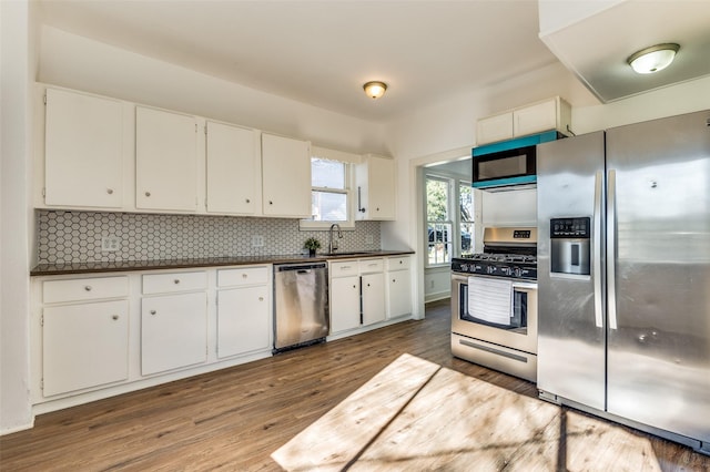 kitchen featuring white cabinetry, sink, light hardwood / wood-style floors, decorative backsplash, and appliances with stainless steel finishes