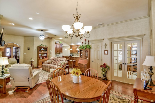 dining area with crown molding, wood-type flooring, french doors, and ceiling fan with notable chandelier