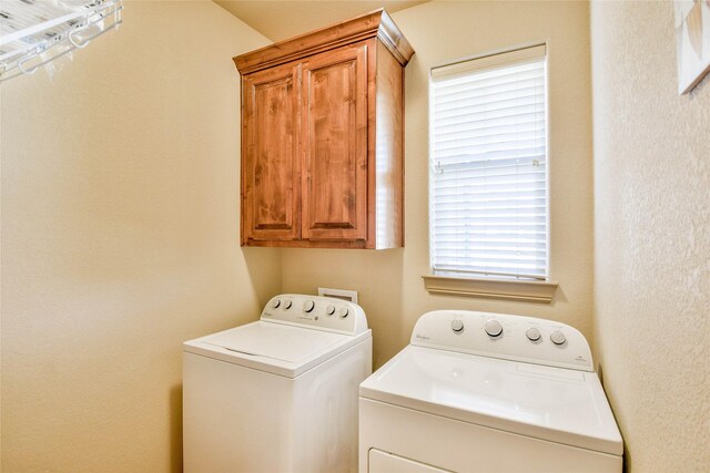 clothes washing area featuring cabinets and independent washer and dryer