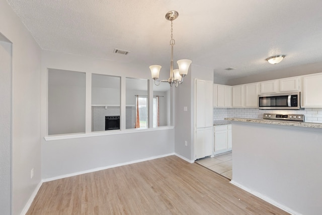 kitchen with hanging light fixtures, tasteful backsplash, and white cabinets