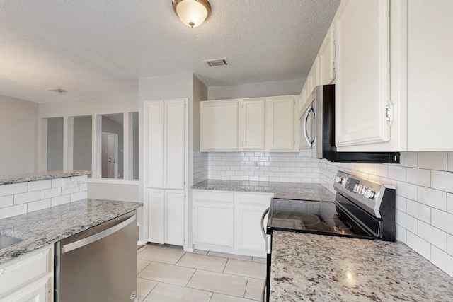 kitchen with stainless steel appliances, white cabinetry, light stone countertops, and tasteful backsplash