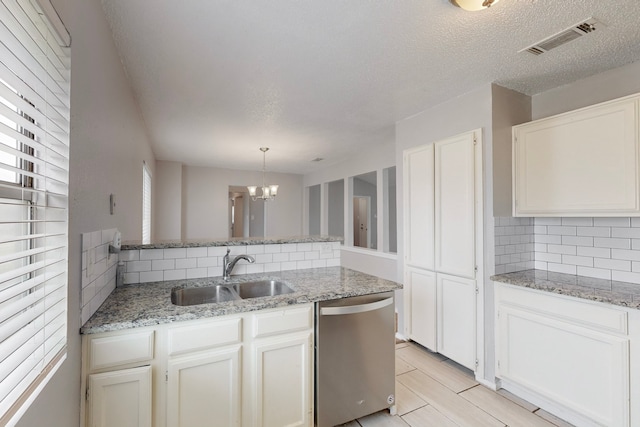 kitchen with sink, dishwasher, hanging light fixtures, light stone counters, and white cabinets