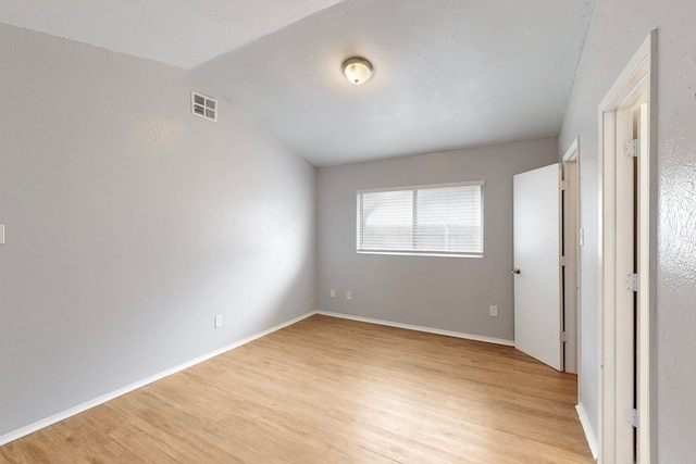 unfurnished bedroom featuring vaulted ceiling and light hardwood / wood-style floors