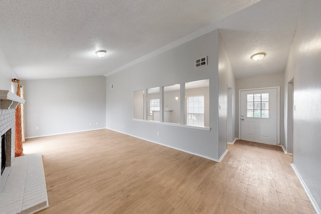 unfurnished living room featuring lofted ceiling, light hardwood / wood-style floors, and a brick fireplace