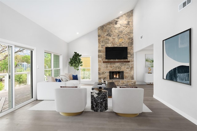 living room featuring a fireplace, wood-type flooring, high vaulted ceiling, and plenty of natural light