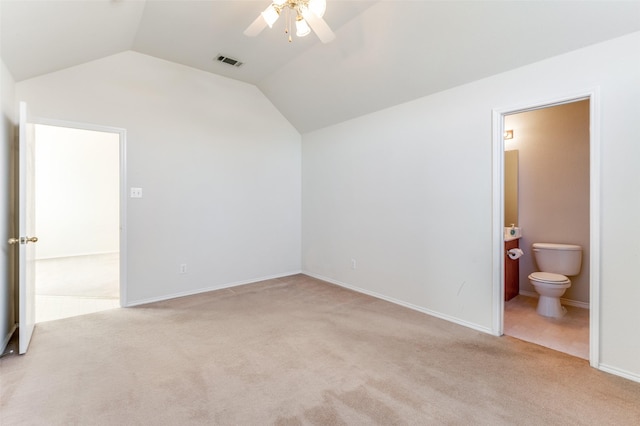 unfurnished bedroom with connected bathroom, ceiling fan, light colored carpet, and vaulted ceiling