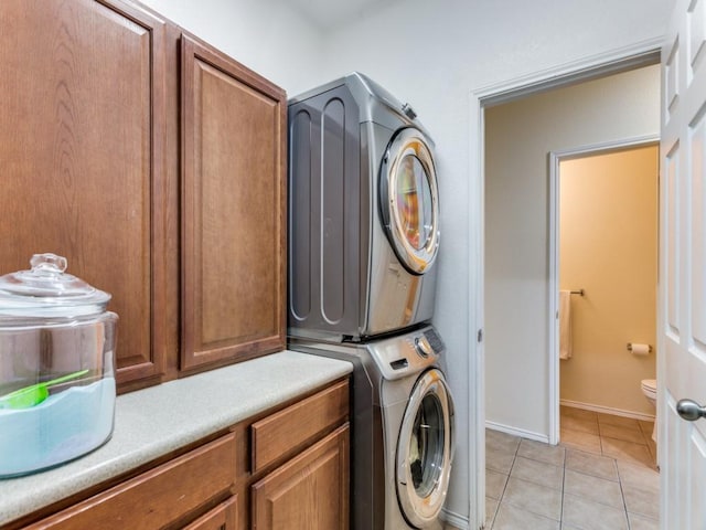 laundry area featuring light tile patterned flooring, cabinets, and stacked washer / dryer