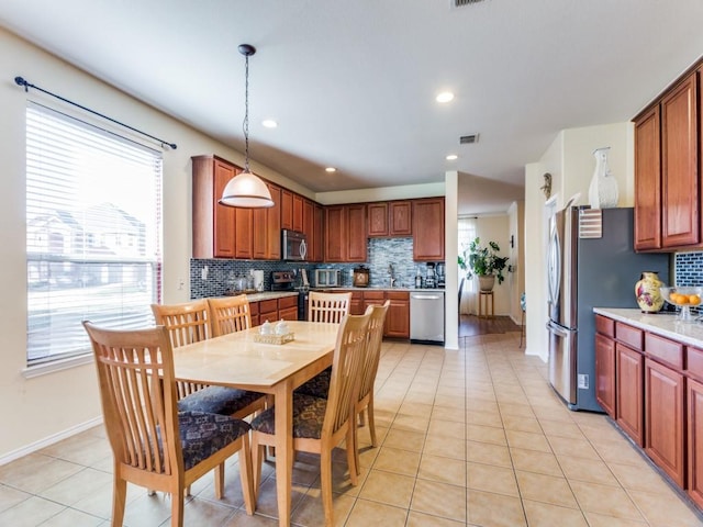 kitchen with pendant lighting, light tile patterned floors, stainless steel appliances, and a wealth of natural light