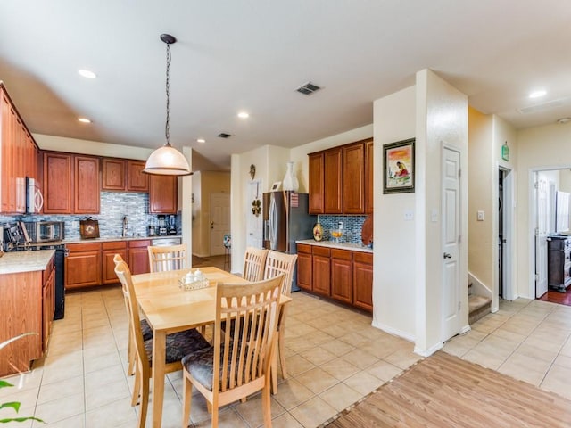 kitchen featuring pendant lighting, tasteful backsplash, stainless steel appliances, and light tile patterned flooring