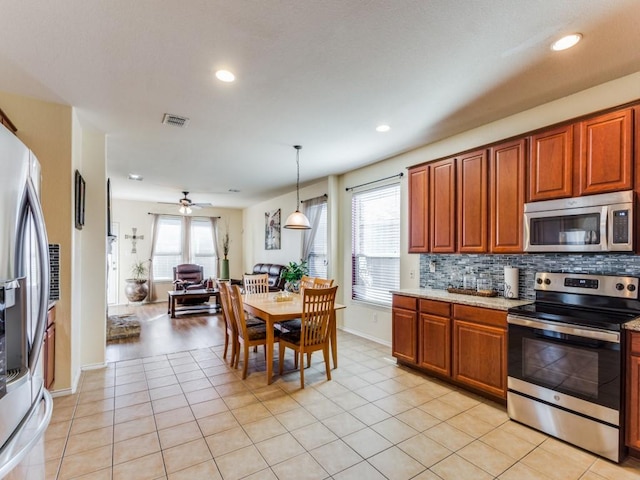 kitchen featuring backsplash, ceiling fan, decorative light fixtures, light tile patterned flooring, and stainless steel appliances