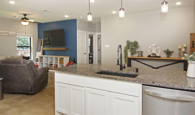 kitchen featuring light stone countertops, sink, stainless steel dishwasher, pendant lighting, and white cabinets