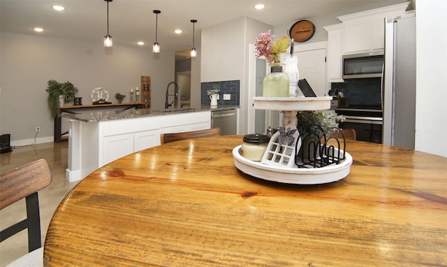 kitchen featuring backsplash, dark stone counters, stainless steel appliances, sink, and white cabinets