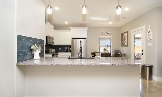 kitchen with appliances with stainless steel finishes, backsplash, light stone counters, decorative light fixtures, and white cabinets