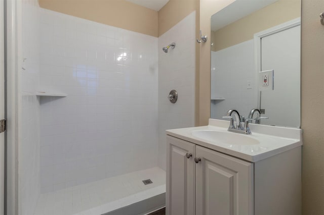 bathroom featuring tiled shower and vanity