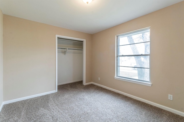 unfurnished bedroom featuring multiple windows, carpet flooring, and a closet