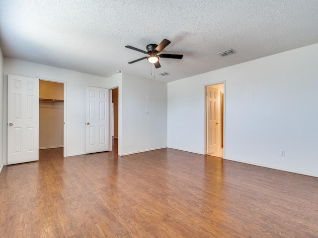 unfurnished room with ceiling fan, wood-type flooring, and a textured ceiling