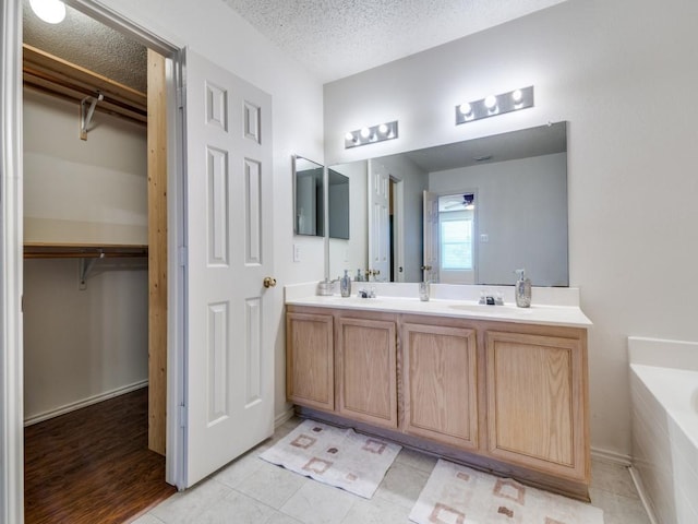 bathroom with tile patterned floors, vanity, a bath, and a textured ceiling