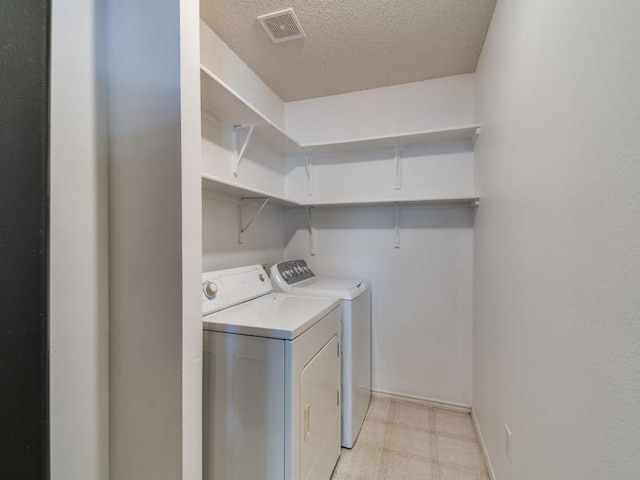 washroom featuring a textured ceiling and washing machine and dryer