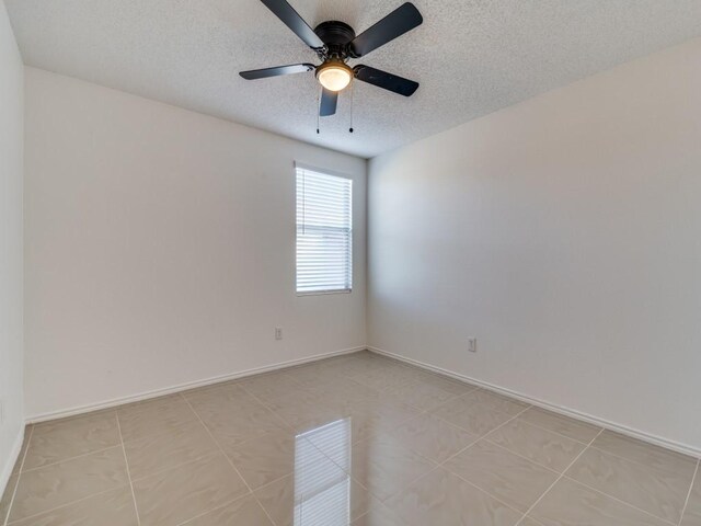 tiled empty room featuring ceiling fan and a textured ceiling