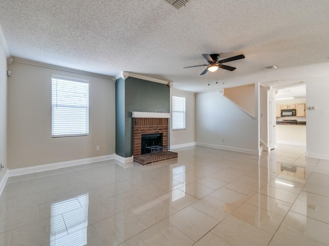 unfurnished living room with a brick fireplace, a textured ceiling, ceiling fan, crown molding, and light tile patterned floors