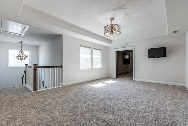 unfurnished room featuring a tray ceiling, a wealth of natural light, and a chandelier