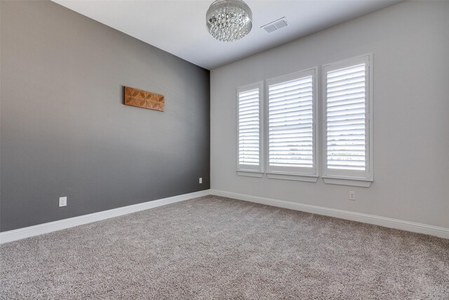 spare room with carpet floors and an inviting chandelier