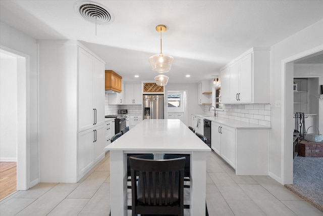 kitchen featuring white cabinetry, hanging light fixtures, backsplash, and stainless steel appliances