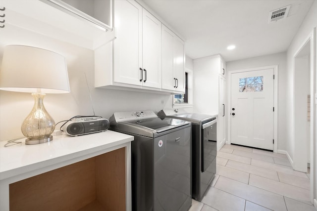 laundry room with cabinets, light tile patterned floors, and washing machine and clothes dryer