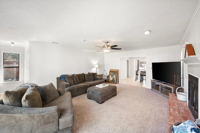 living room featuring ornamental molding, a fireplace, light colored carpet, and ceiling fan