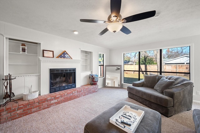 living room featuring built in shelves, carpet flooring, a brick fireplace, and a textured ceiling