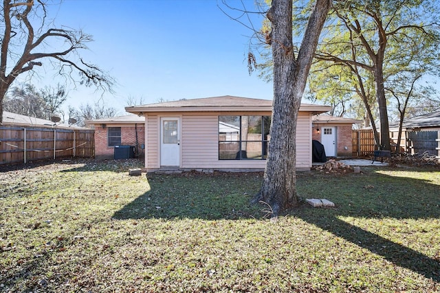 rear view of house with cooling unit and a yard