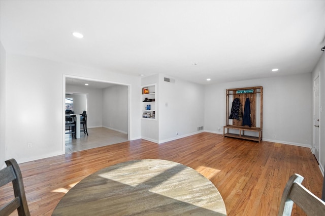 living room with light wood-type flooring and built in shelves