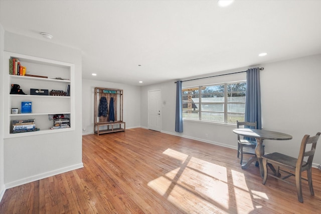 living room featuring light wood-type flooring and built in shelves