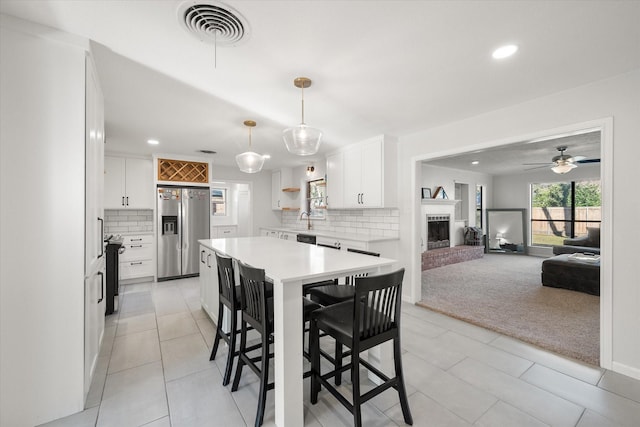 dining area featuring light carpet, sink, a fireplace, and ceiling fan